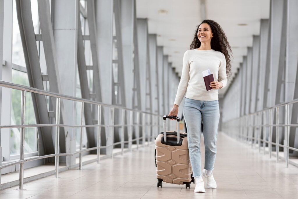 Femme marchant dans le terminal des navires de croisière avec bagages et passeport à la main