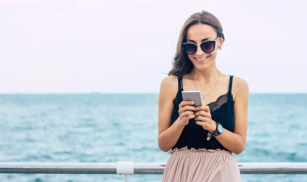 Femme envoyant des SMS sur un bateau de croisière avec l'horizon en arrière-plan