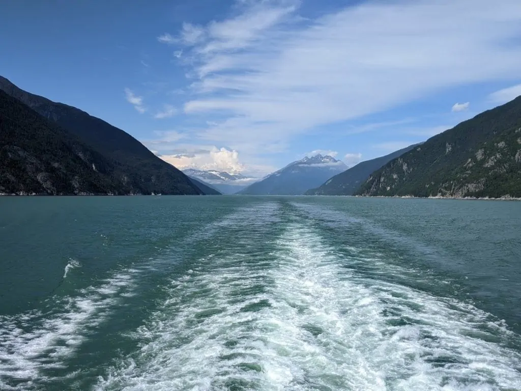 Vue de la côte de l'Alaska depuis l'arrière d'un bateau de croisière avec le sillage derrière le navire