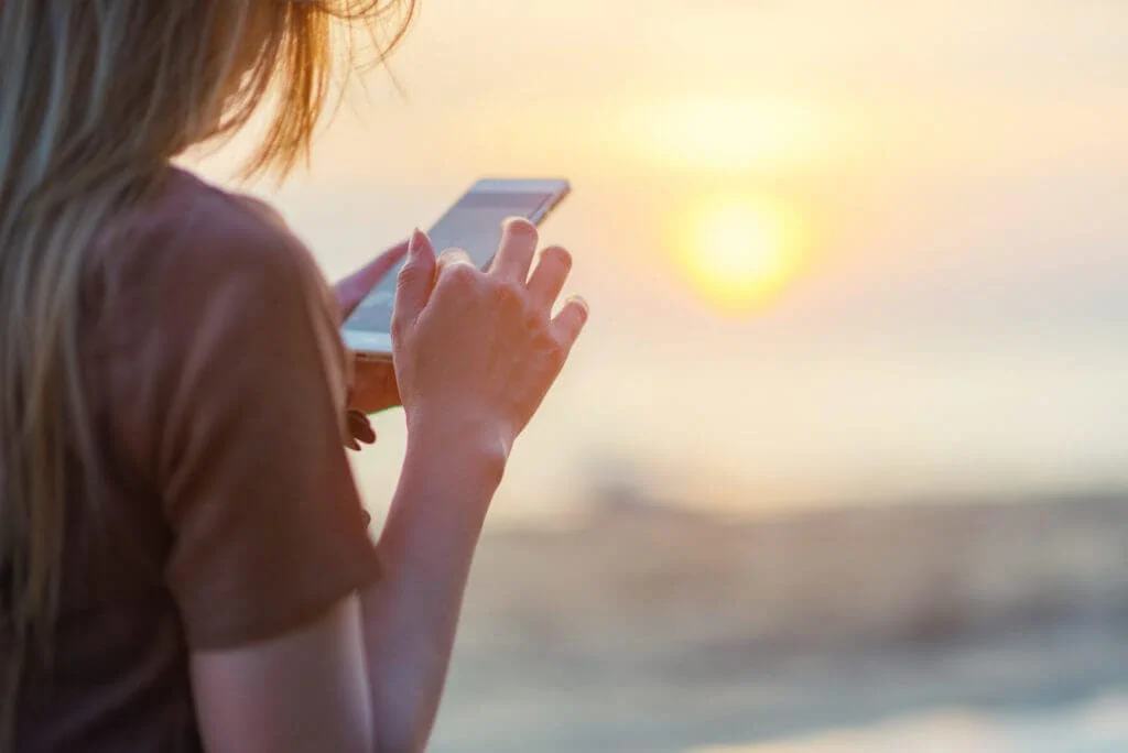 Femme sur un bateau de croisière utilisant son téléphone pour prendre une photo du coucher de soleil