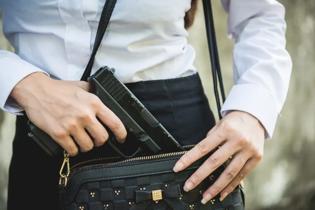 Femme avec un permis de port dissimulé mettant une arme à feu dans son sac à main