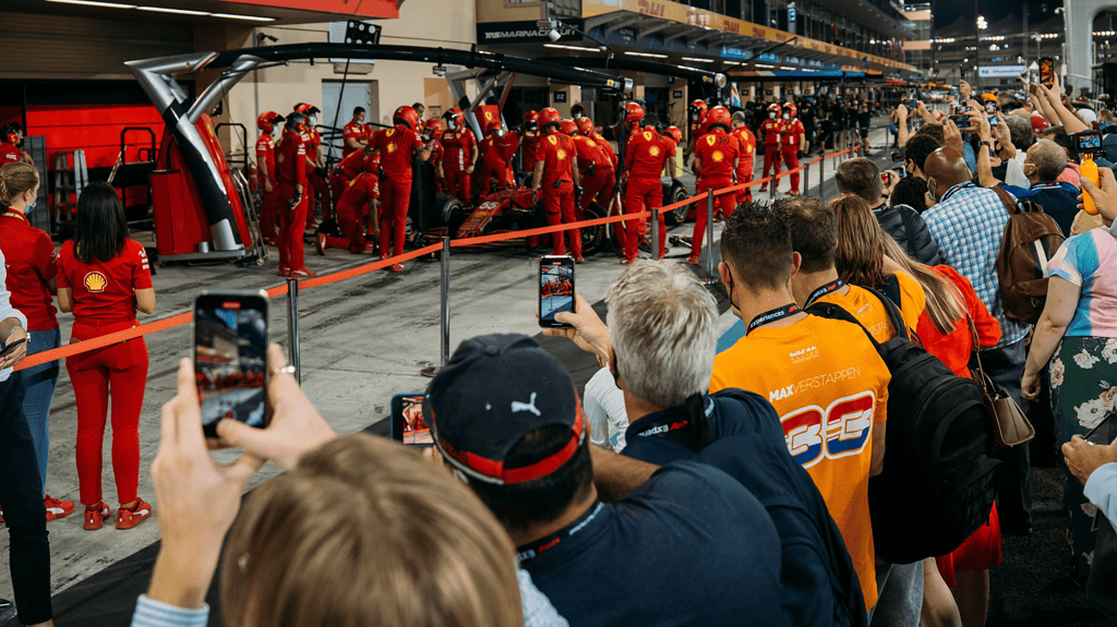 promenade dans la voie des stands de Formule 1 avec l'équipe Ferrari en arrière-plan